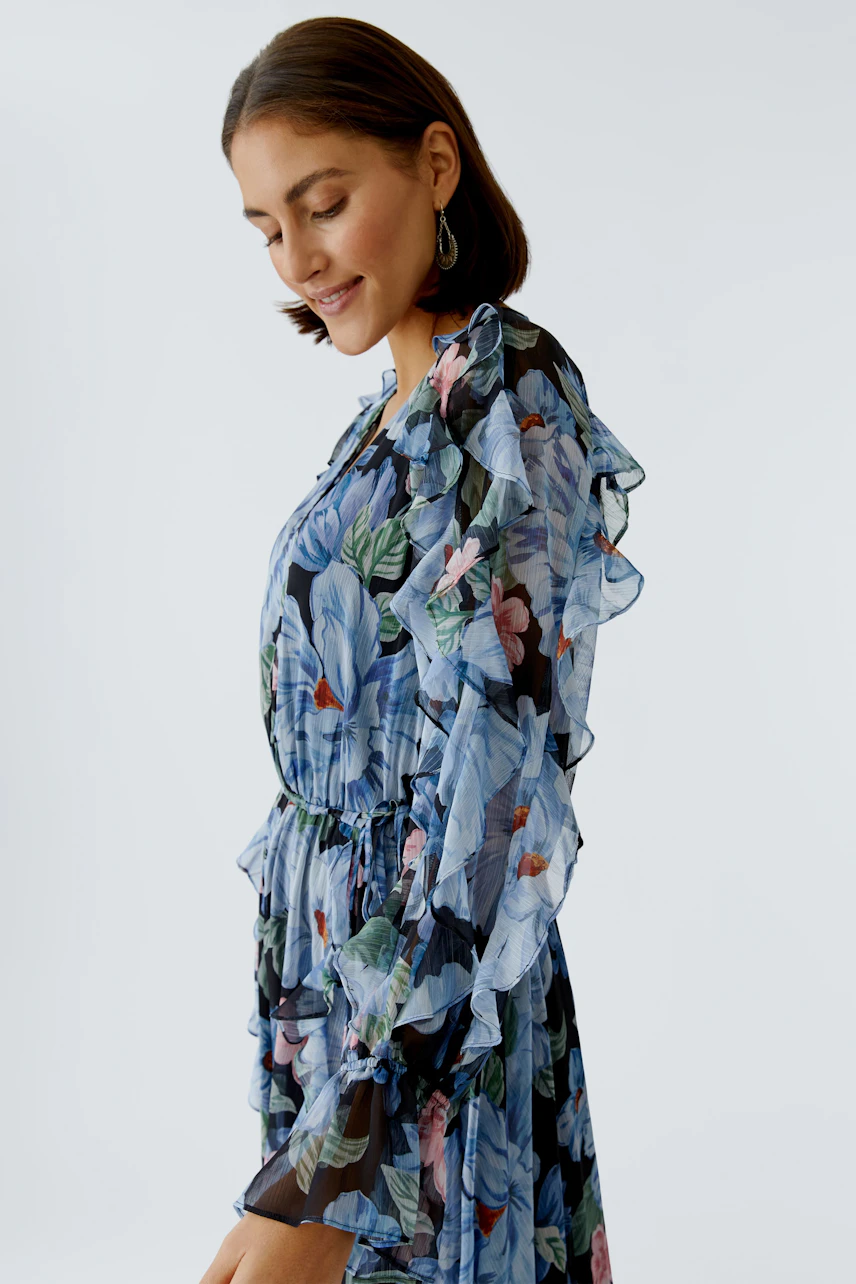 Floral maxi dress: Woman in a flowing dress with ruffles and vibrant flowers, showcasing a relaxed style.