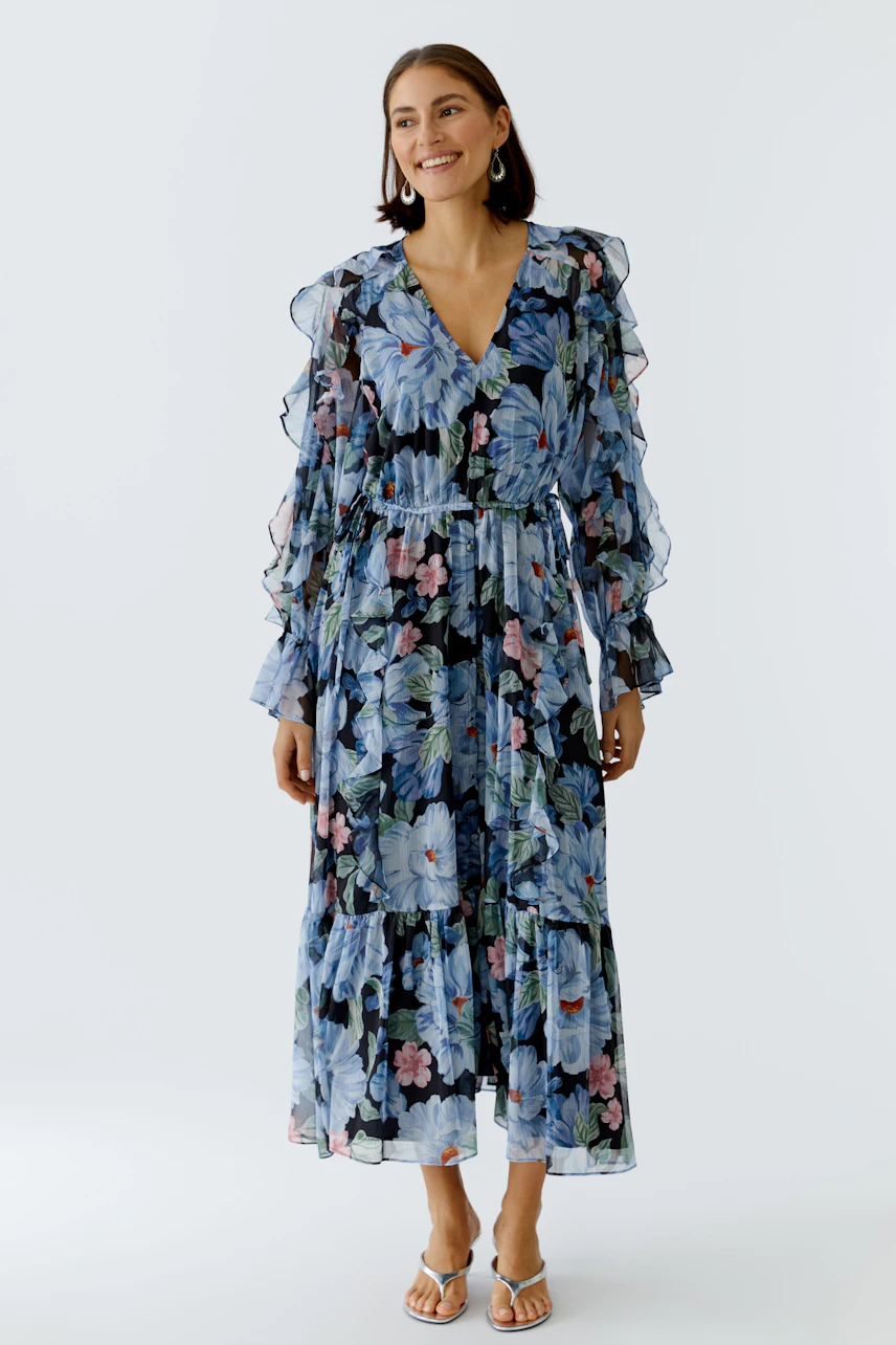 Floral maxi dress: Woman in a flowing dress with ruffled sleeves and vibrant floral print.