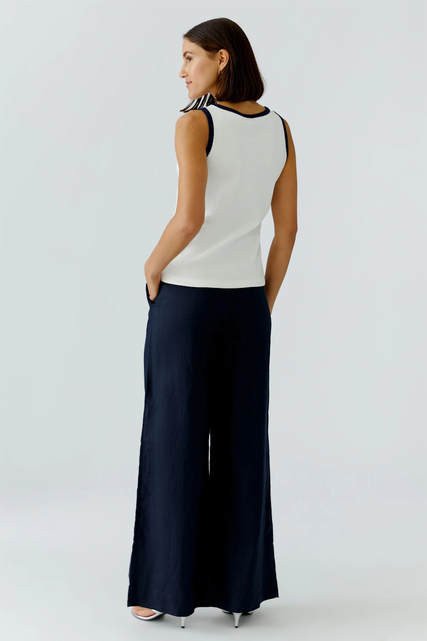 Casual women's tank top: A woman in a white tank top with navy accents, paired with wide-leg pants.