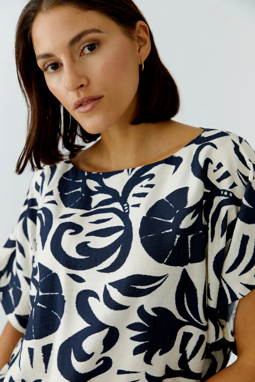 Casual women's blouse: A woman in a loose-fitting blouse with a bold floral pattern.