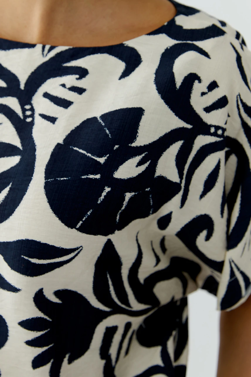 Casual women's blouse with a floral pattern, featuring a relaxed fit and short sleeves.