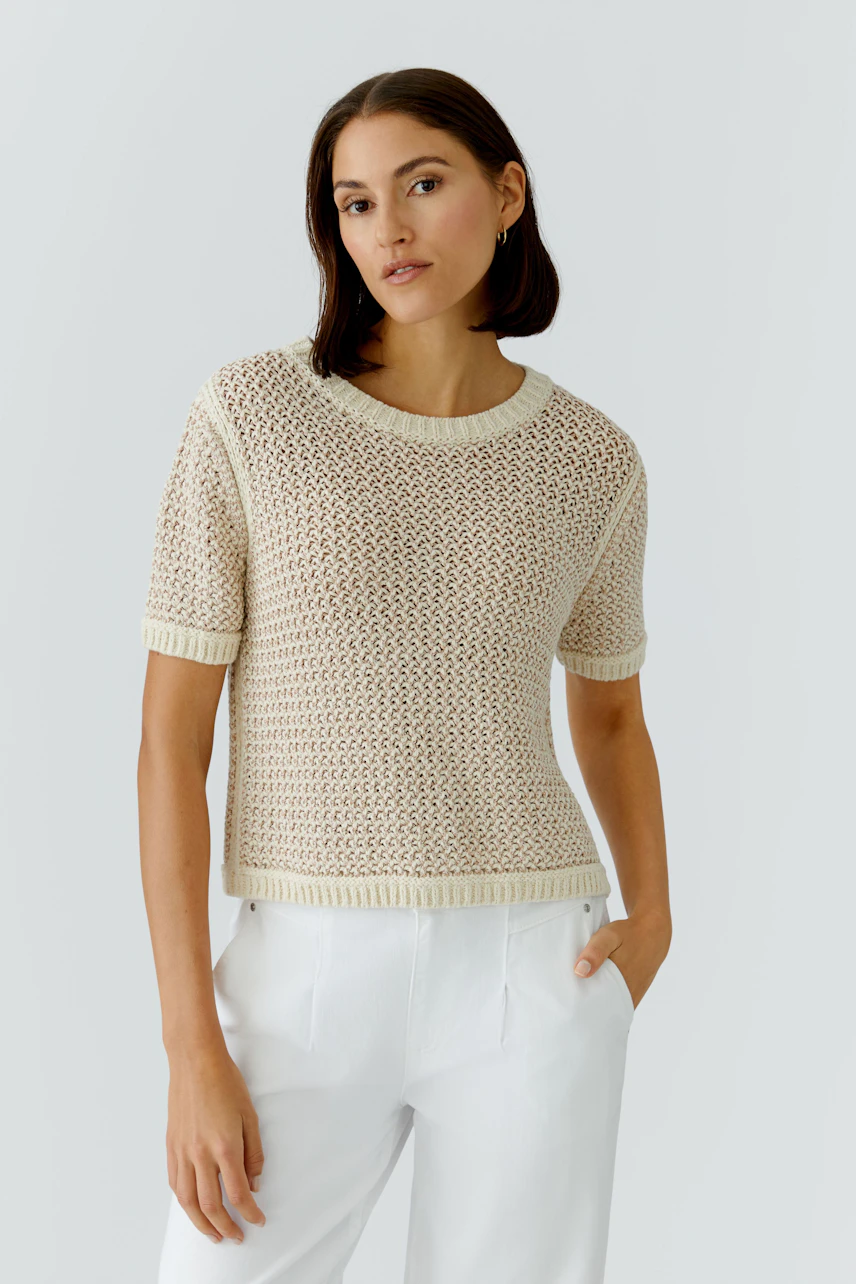 Casual women's pullover: Young woman in a light knitted pullover with short sleeves and relaxed fit.