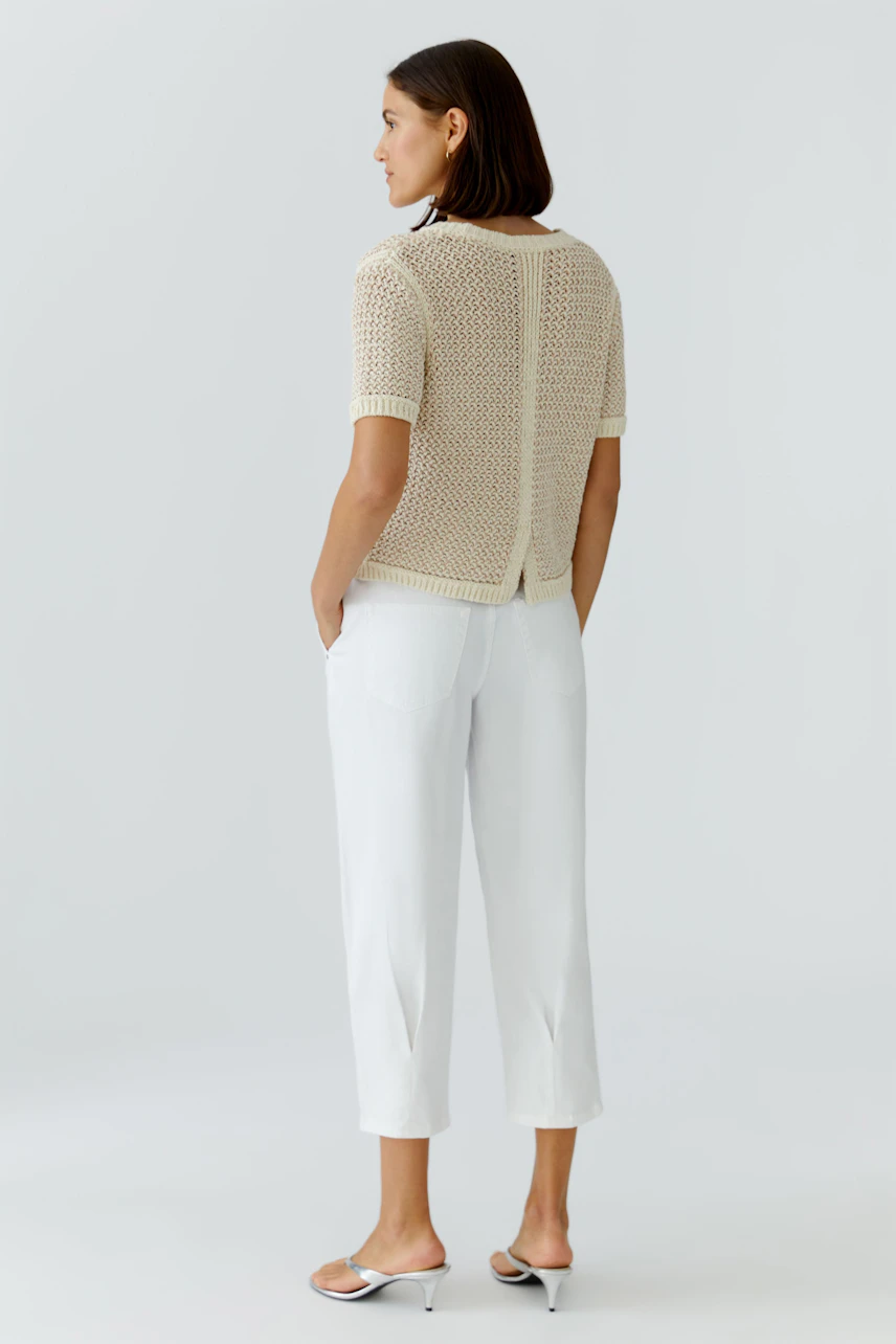 Casual women's pullover: A woman in a light knit pullover with short sleeves and a relaxed fit.