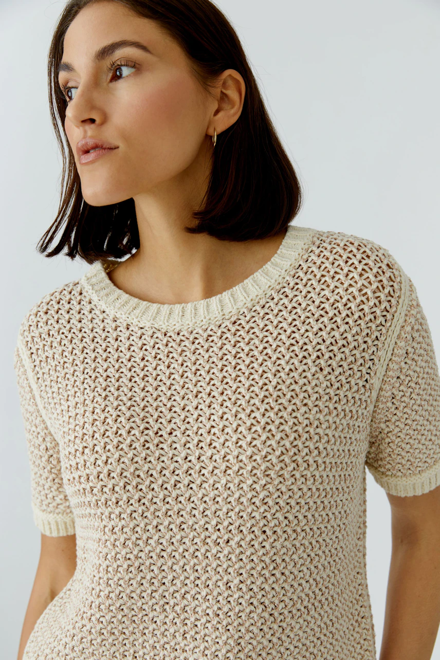 Casual women's pullover: A woman in a light knitted pullover with short sleeves and a relaxed fit.