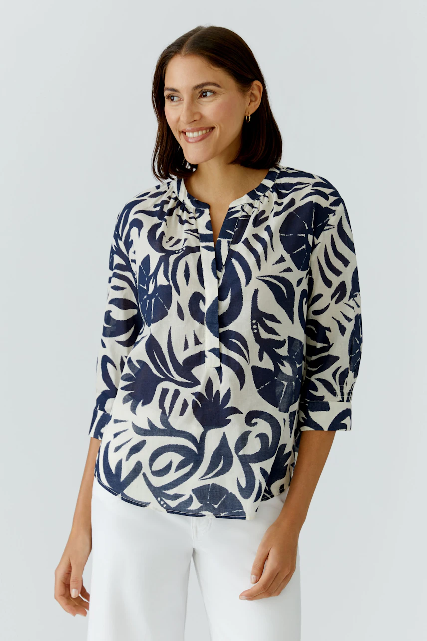 Casual women's tunic: Smiling woman in a patterned tunic with a relaxed fit and three-quarter sleeves.