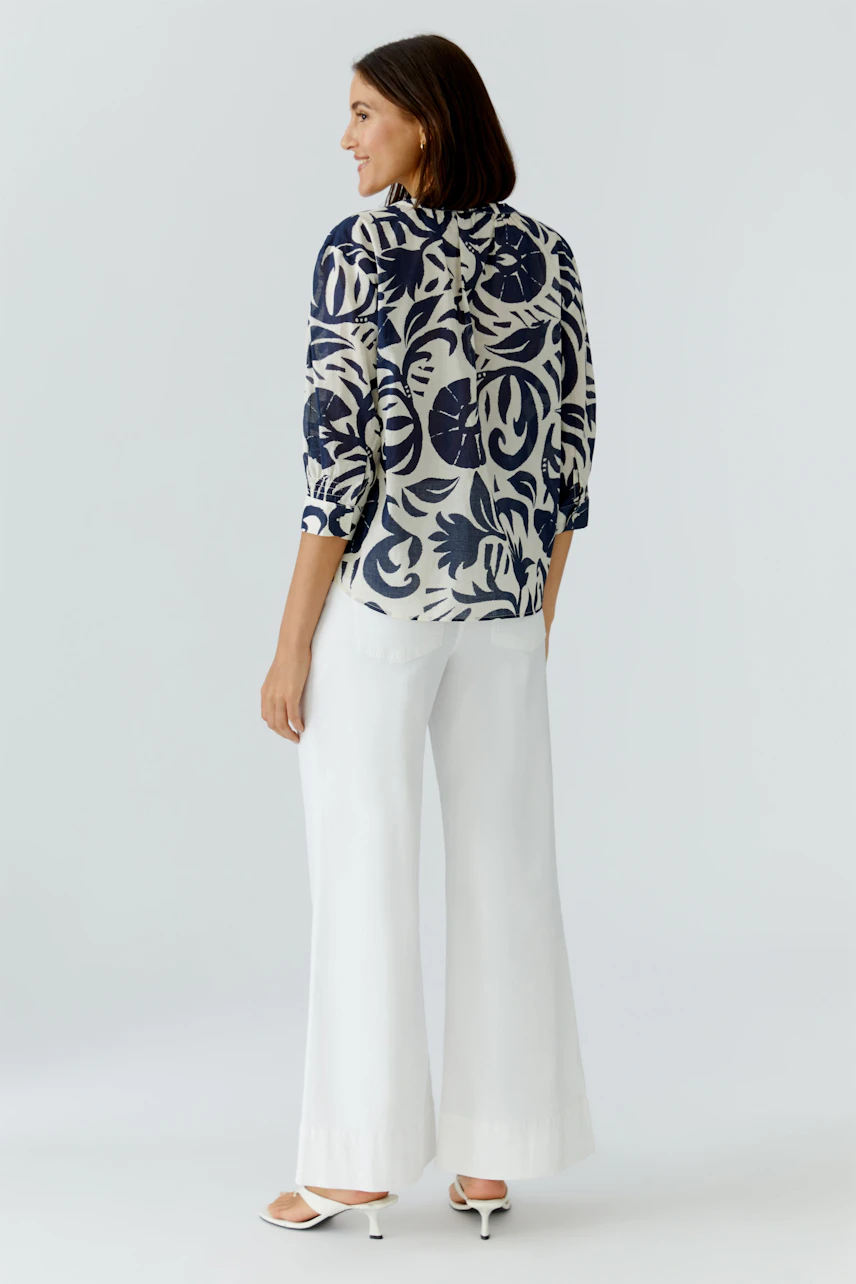 Casual tunic: Woman in a floral-patterned tunic with three-quarter sleeves and wide white pants.