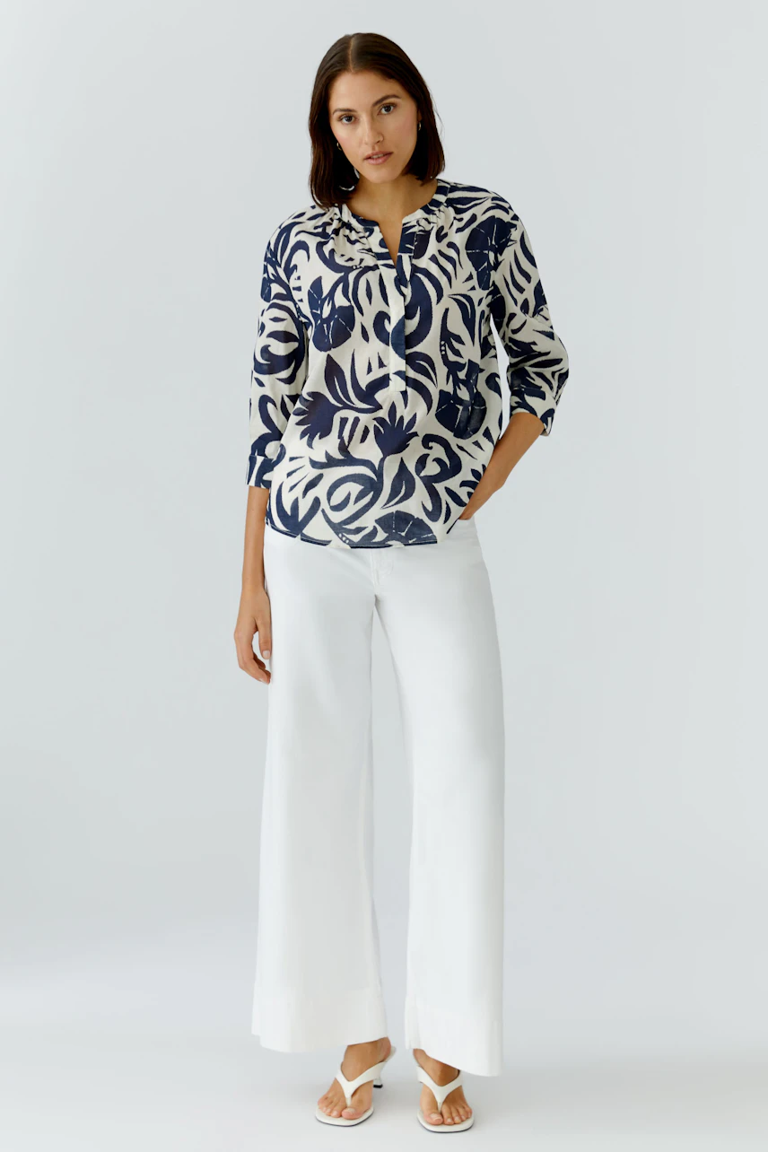 Casual women's tunic: Woman in a patterned tunic with a relaxed fit, paired with wide white pants.