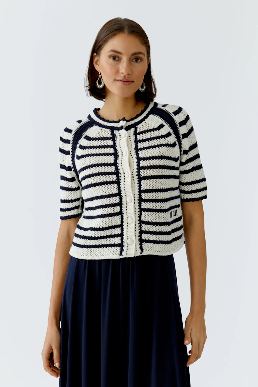 Casual women's cardigan: A woman in a striped short-sleeve cardigan over a long dress, smiling confidently.