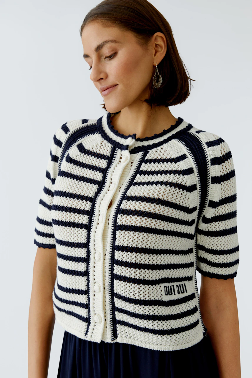 Stylish women's cardigan: A woman in a striped knit cardigan with short sleeves and a button closure.