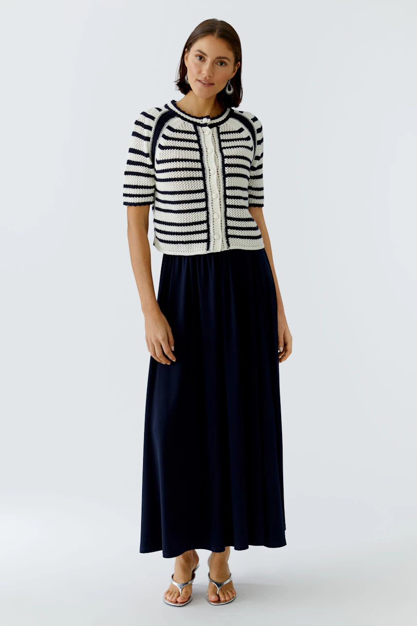 Casual women's cardigan: A woman in a striped short-sleeve cardigan over a long navy dress stands confidently.