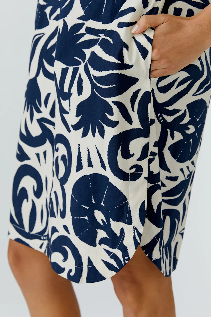 Casual women's dress: Close-up of a woman wearing a navy and white patterned dress with pockets.