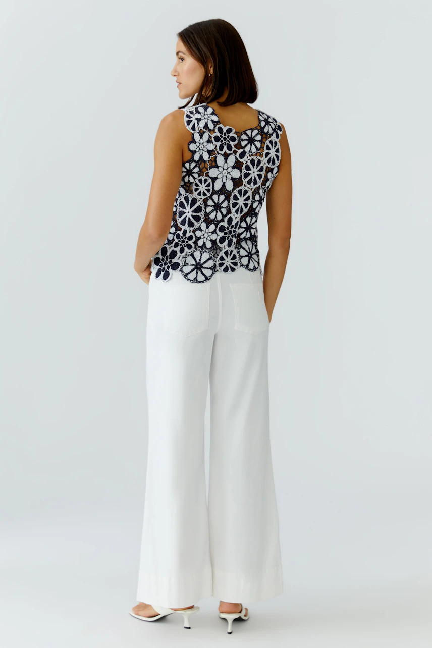 Casual women's top: A woman in a floral-patterned sleeveless top paired with wide white pants.