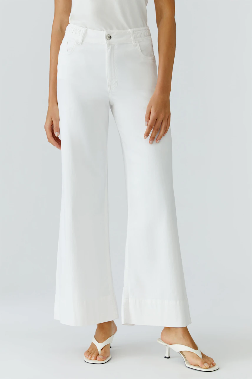 Wide leg jeans for women: A woman in white wide leg jeans paired with a simple top and stylish sandals.