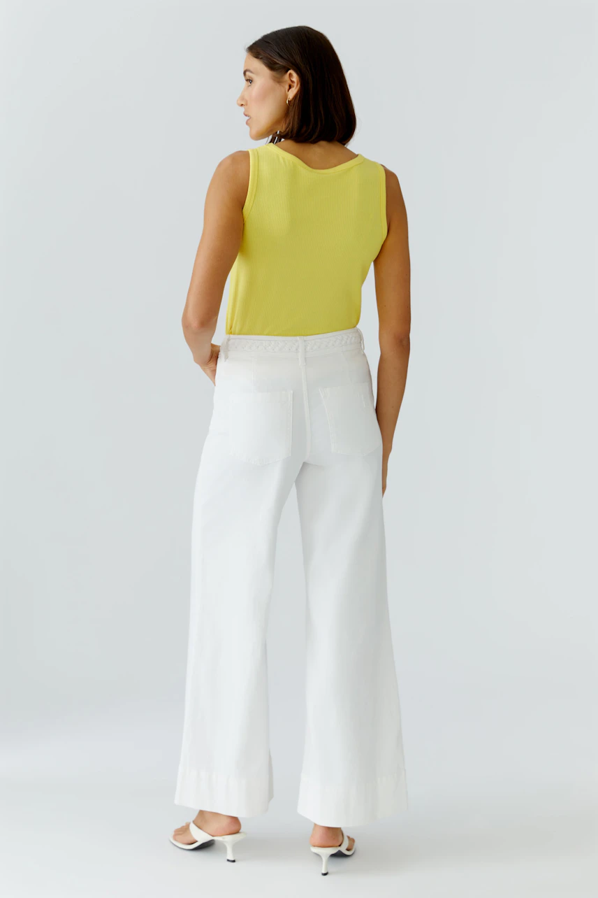 Casual women's top: Woman in a yellow sleeveless top and white wide-leg pants, viewed from the back.