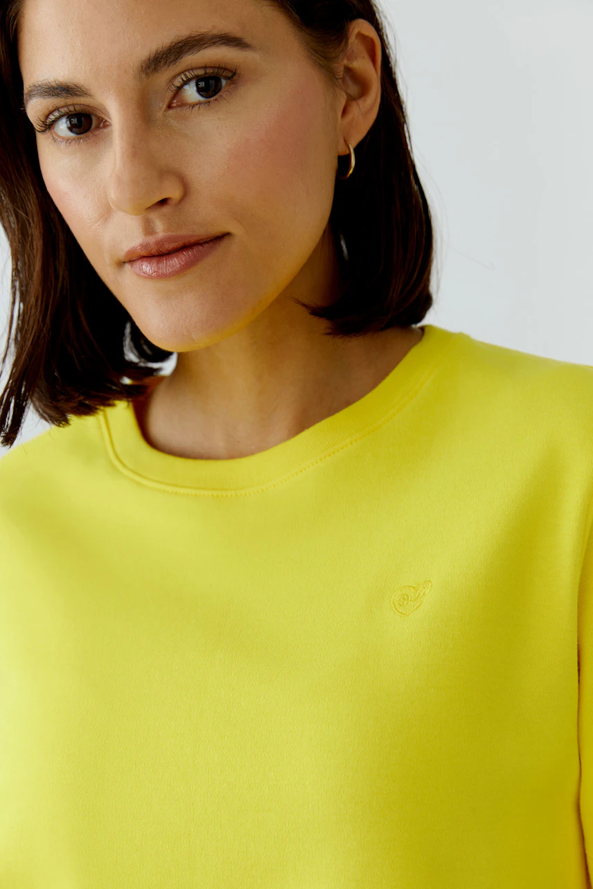 Bright yellow T-shirt: Woman in a casual yellow T-shirt with short hair and a calm expression.