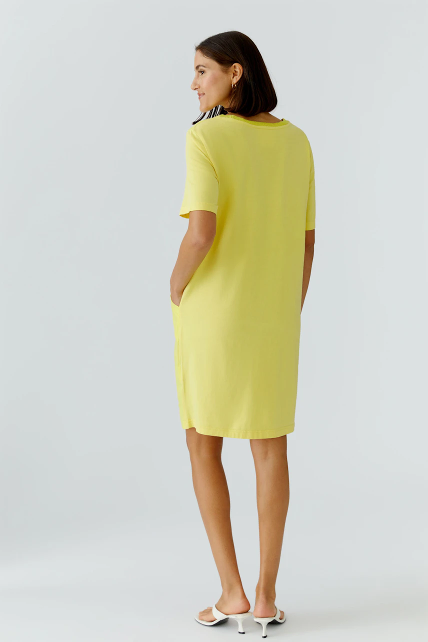 Casual hanger dress: Woman in a yellow dress with short sleeves, standing confidently.