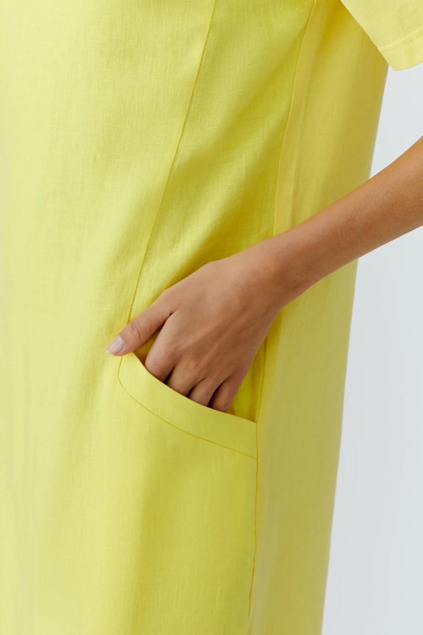 Yellow shift dress: Close-up of a woman's hand in the pocket of a bright yellow dress, showcasing texture.