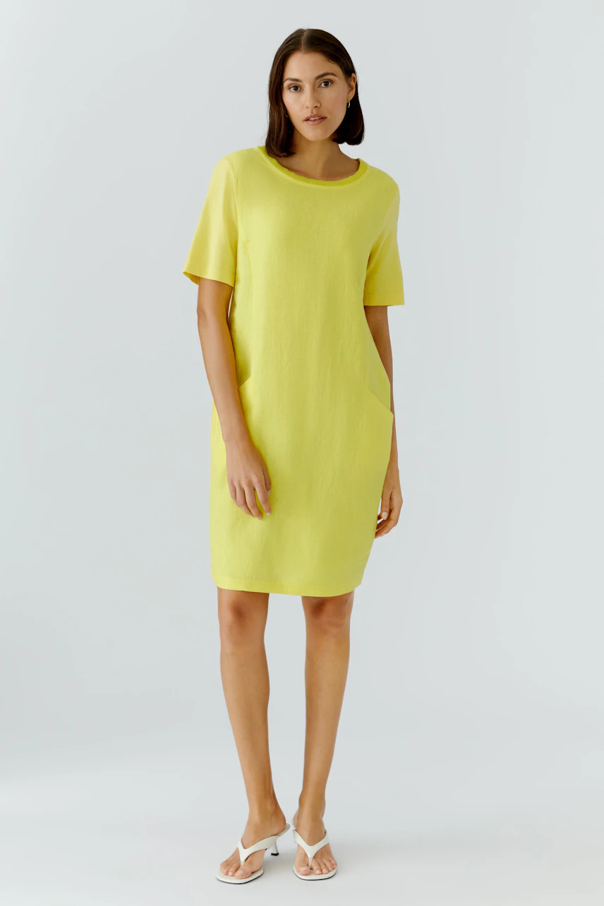 Casual shift dress: Woman in a bright yellow dress with short sleeves and a relaxed fit, standing confidently.