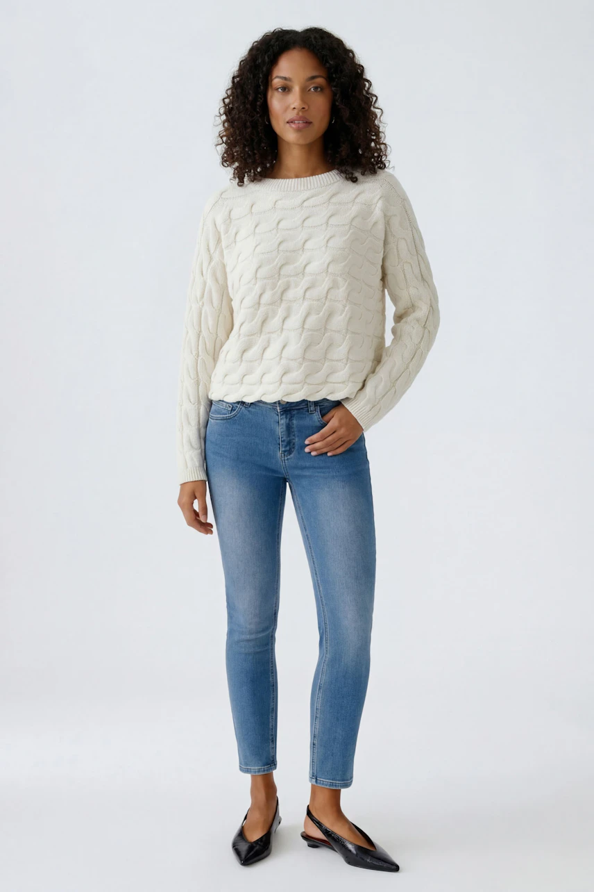 Bequemer Damen-Pullover: Frau in hellem, strukturiertem Strickpullover mit lässiger Passform.