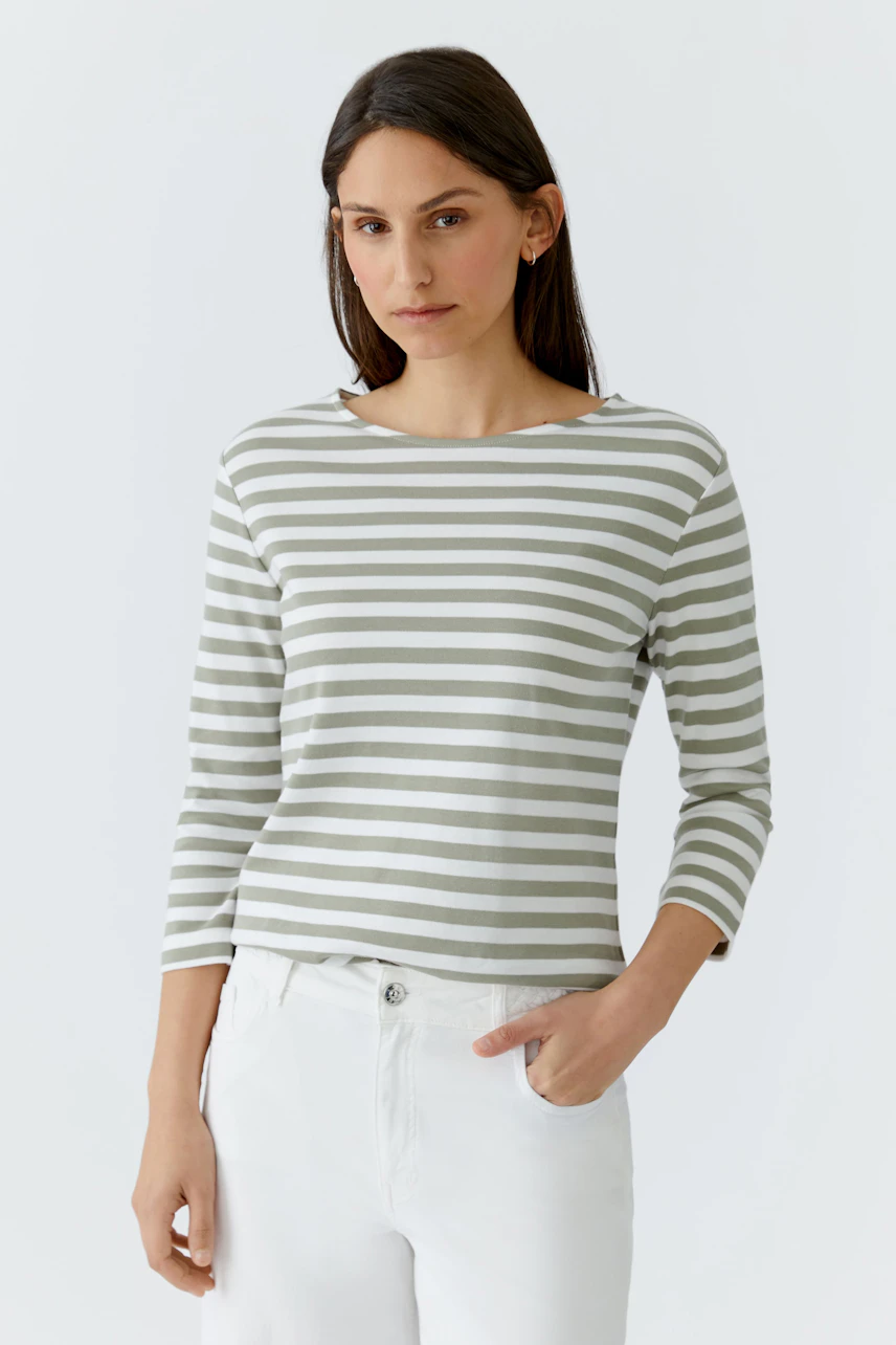 Gestreiftes Damen-T-Shirt: Frau im weiß-grünen Streifen-T-Shirt und weißen Hosen schaut entspannt.