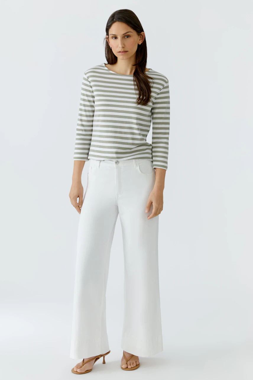Gestreiftes Damen-T-Shirt: Frau im lässigen T-Shirt mit 3/4-Ärmeln und weißen Hosen, entspanntes Auftreten.