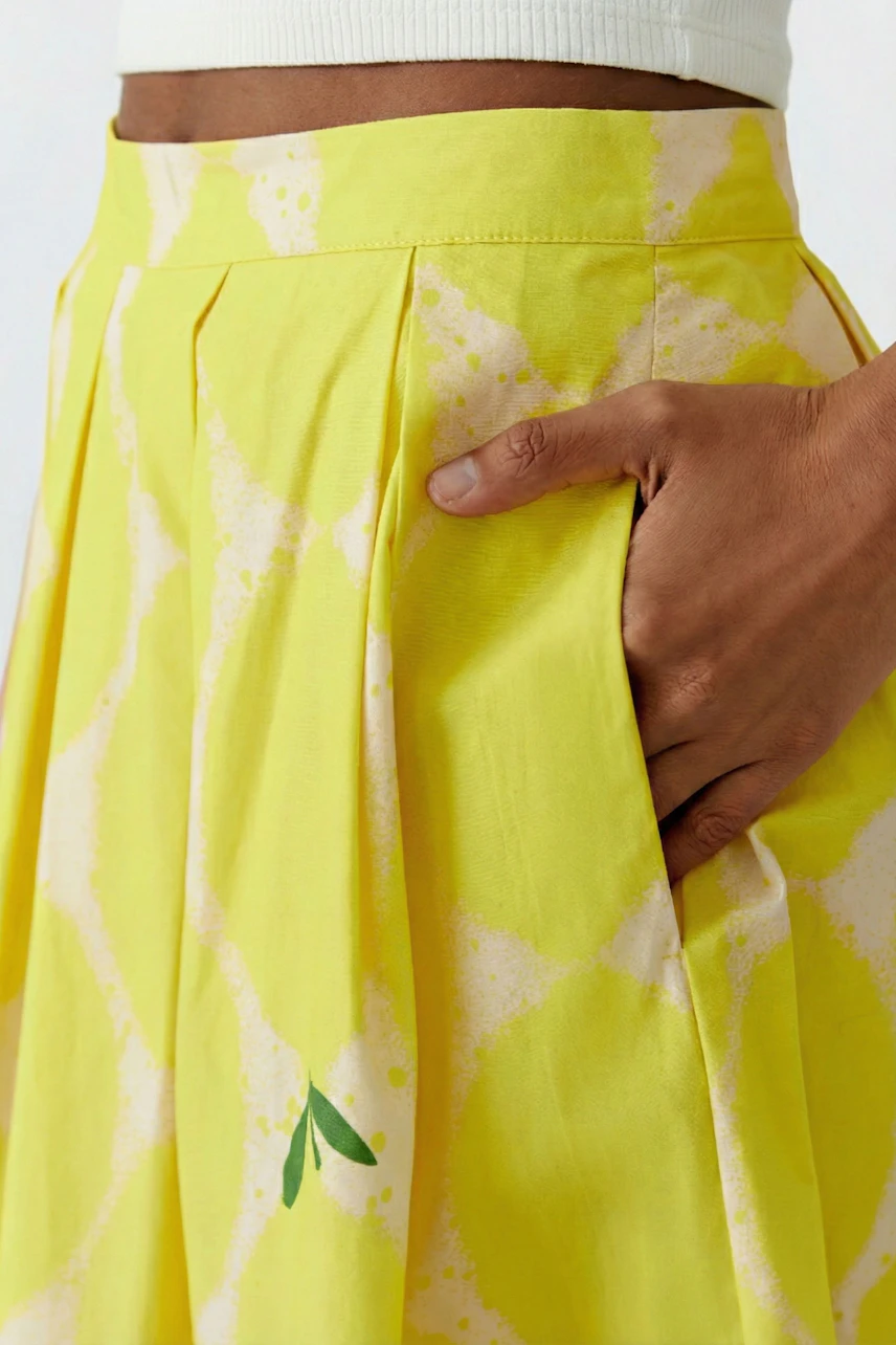 Bright yellow pleated skirt with subtle pattern, worn by a woman, showcasing a casual and vibrant style.
