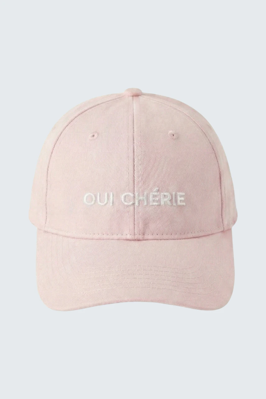 Casual pink hat with 'Oui Chérie' text, perfect for a relaxed, stylish look.
