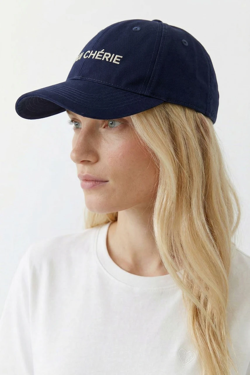 Damen-Hut: Frau mit blauem Baseballcap und weißem T-Shirt blickt zur Seite.