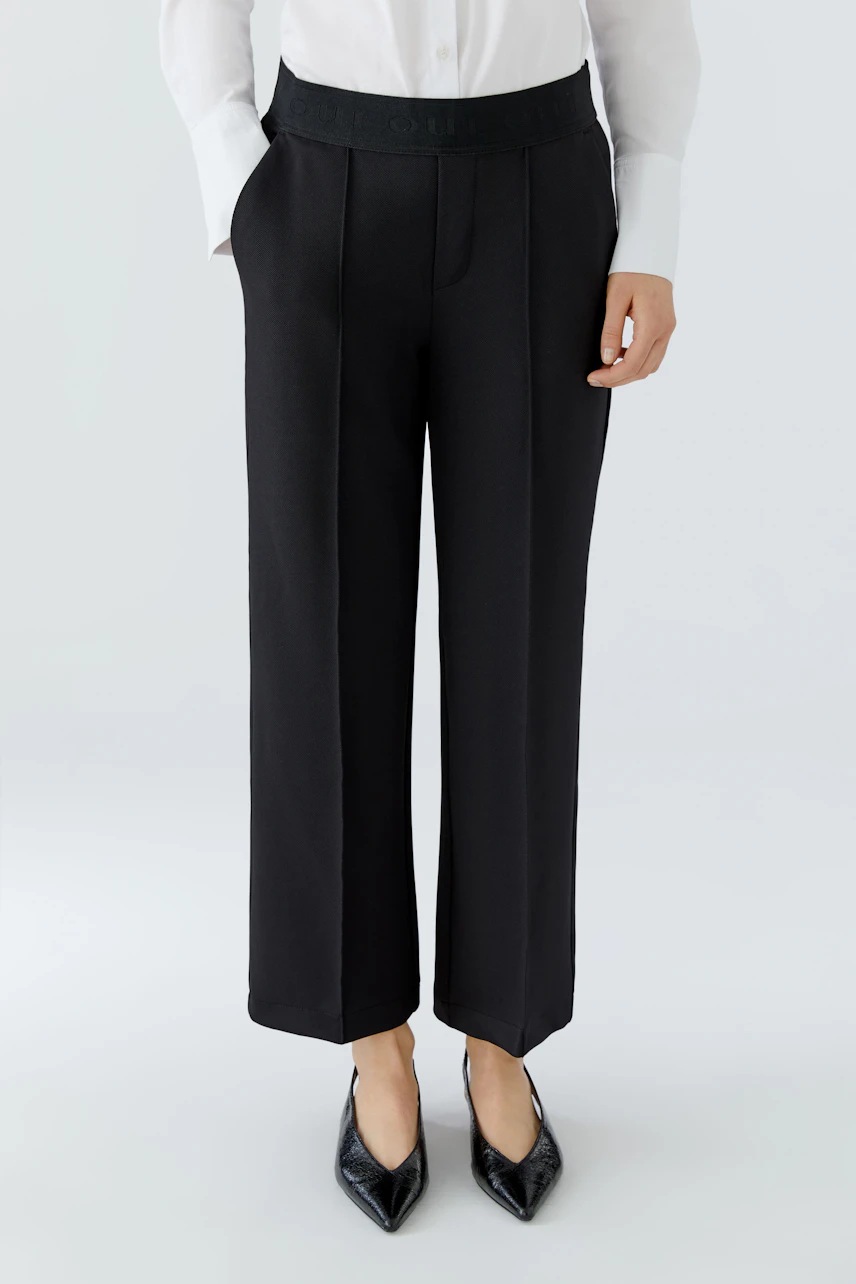 Modern culotte: Woman in black wide-leg pants with a comfortable waistband, paired with a classic shirt.