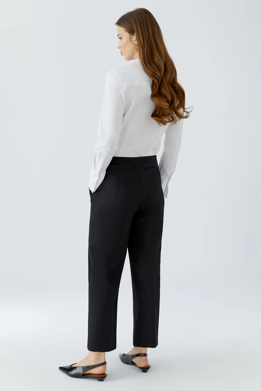 Chic culotte: Woman in black culottes paired with a white shirt, showcasing a relaxed fit.