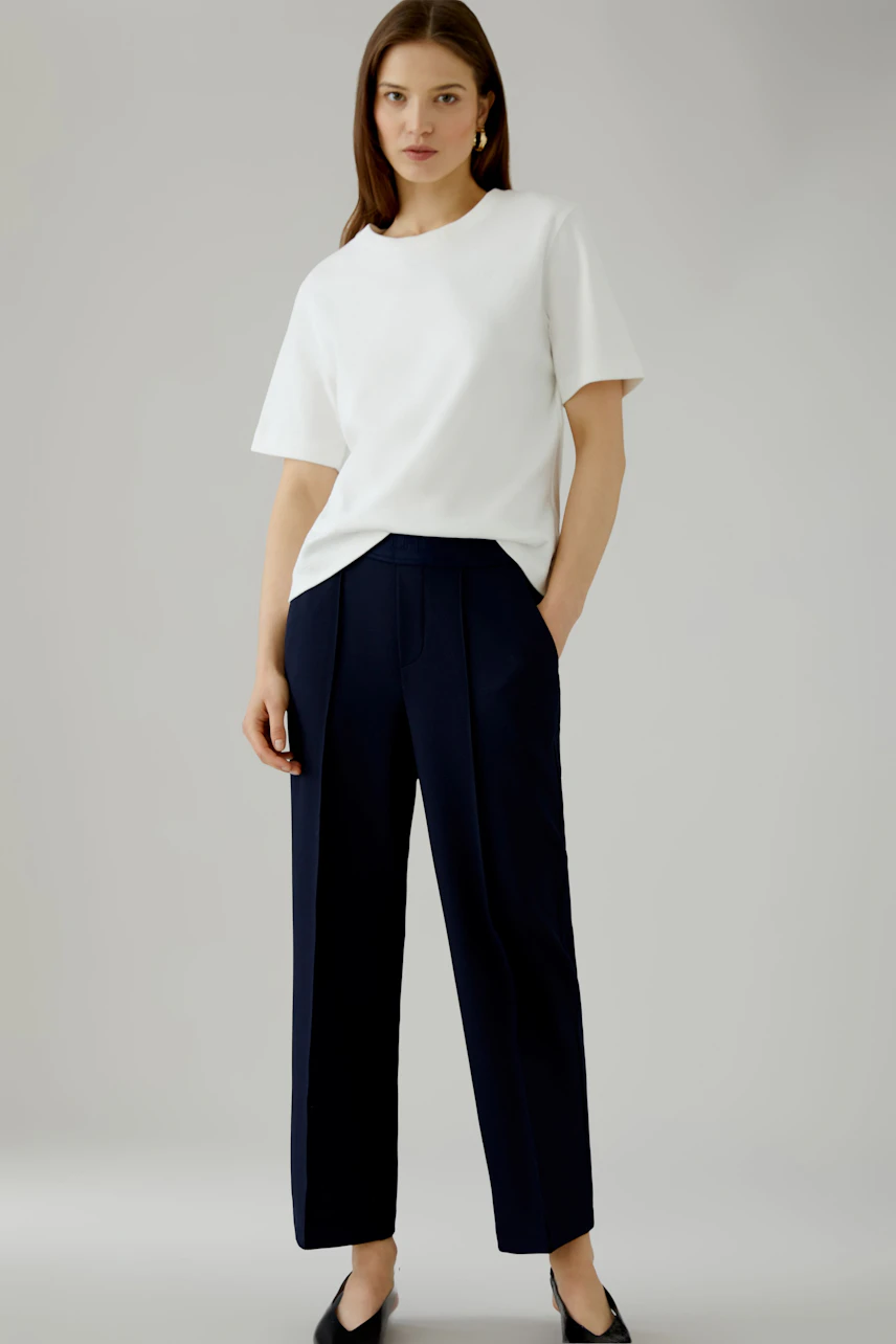 Woman in white shirt and black culotte, smiling confidently. Casual and stylish look.