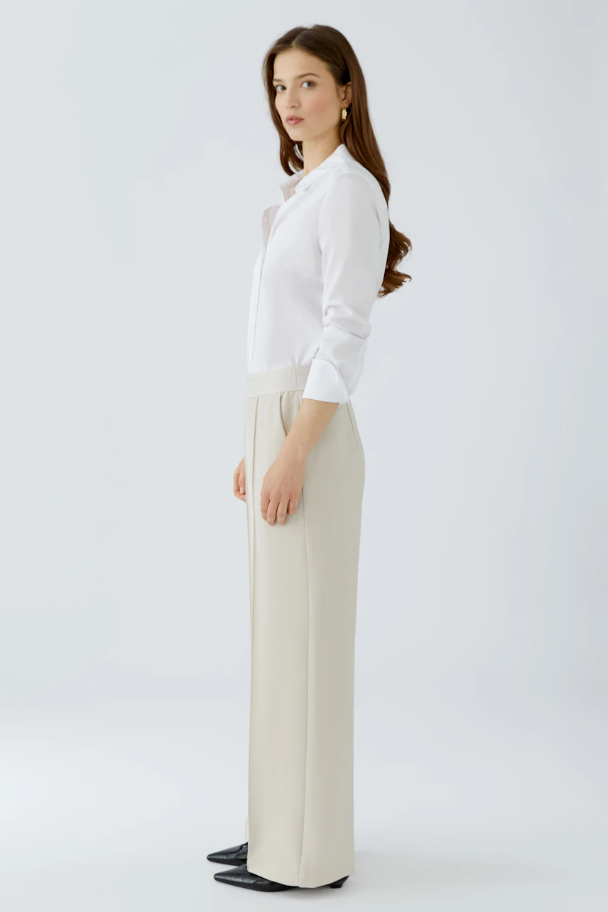 Casual women's trousers: A woman in light beige trousers with a comfortable waistband and a classic white shirt.