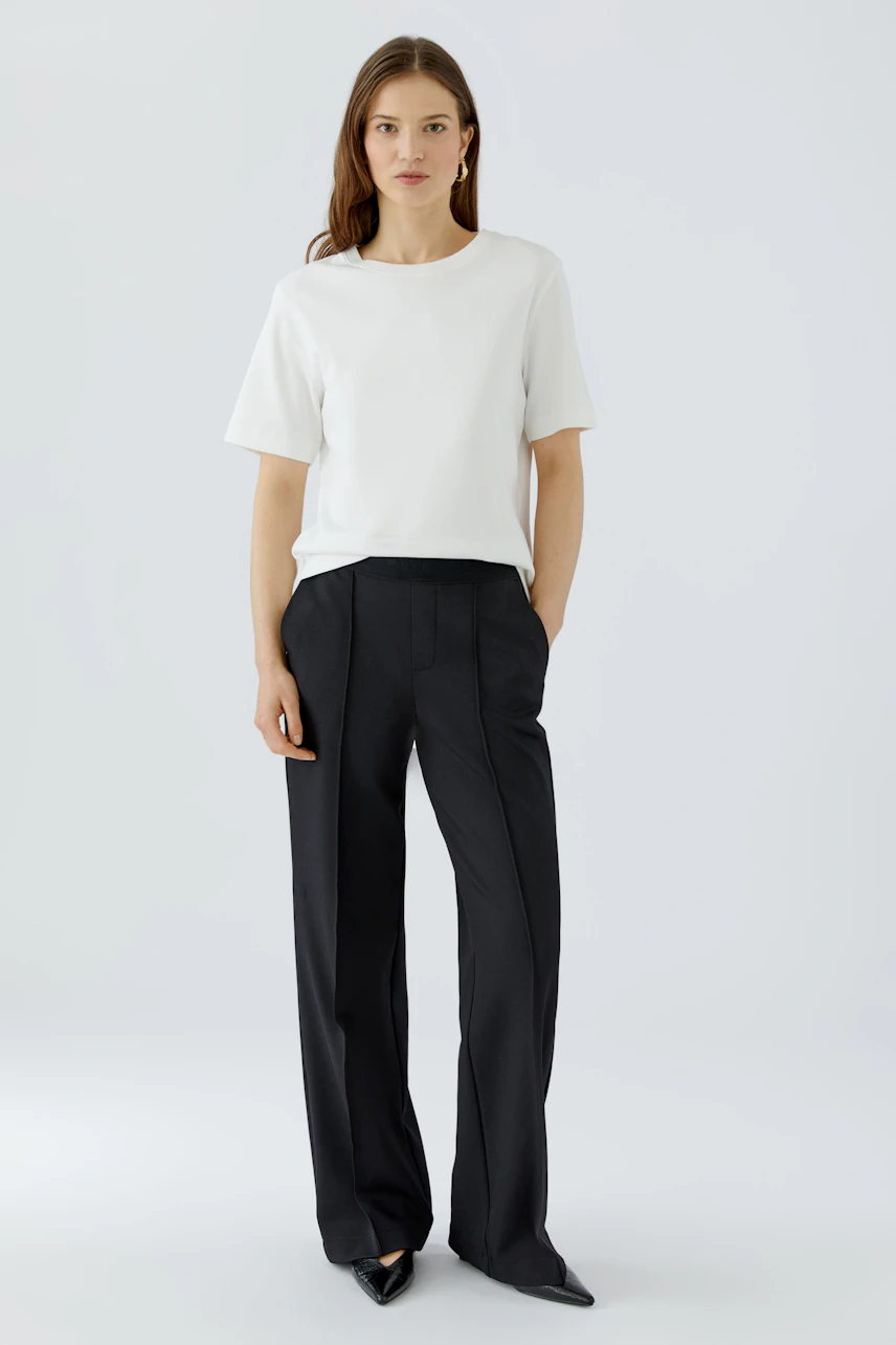 Casual women's trousers: A woman in black wide-leg trousers with a white top, standing confidently.