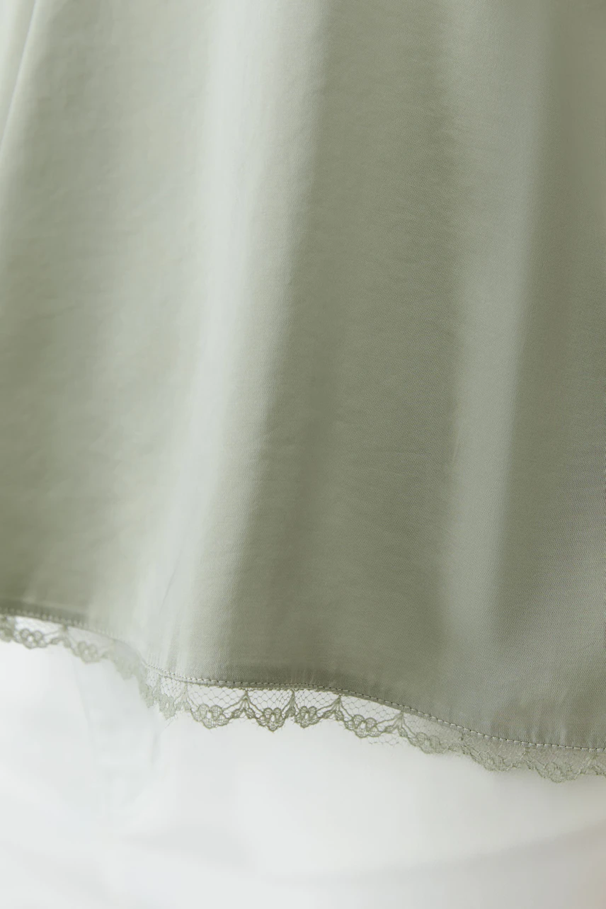 Casual women's top: Light green top with delicate lace hem, perfect for layering.