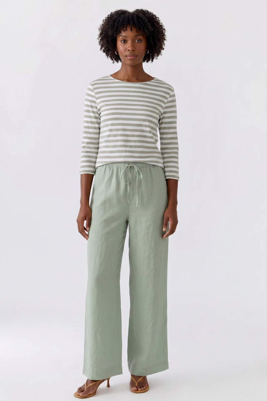 Woman in relaxed Marlene pants and matching top, smiling confidently. Casual and comfortable style.