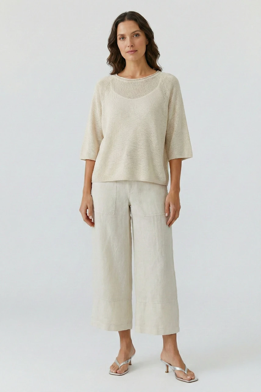 Lässige Damen-Hose: Frau in weiter, beiger Hose und passendem Oberteil, steht entspannt.