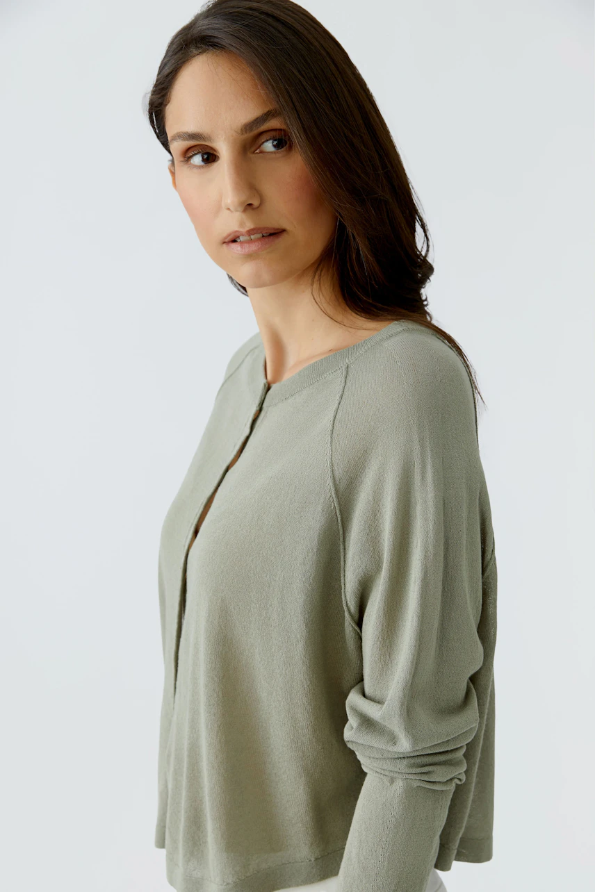 Damen-Strickjacke: Frau in olivgrüner Strickjacke mit Knopfleiste, lässig und modern.