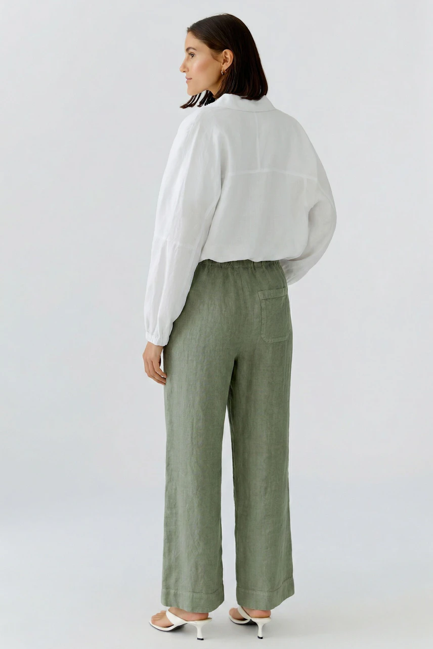 Casual blouson: Woman in a white blouson with brown shorts and white sandals, looking relaxed.
