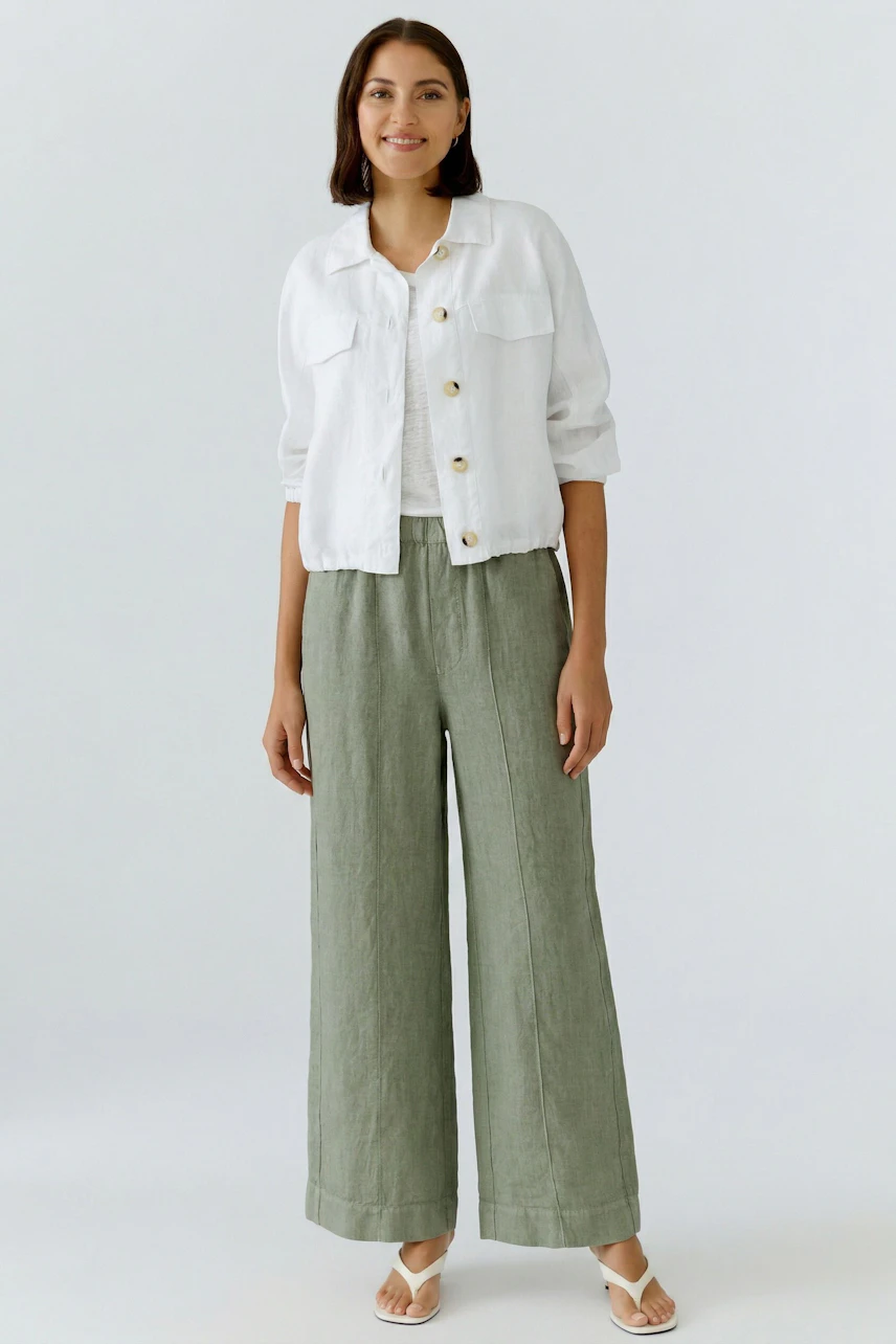 Casual blouson: Woman in a white button-up blouson, brown shorts, and sandals, smiling confidently.