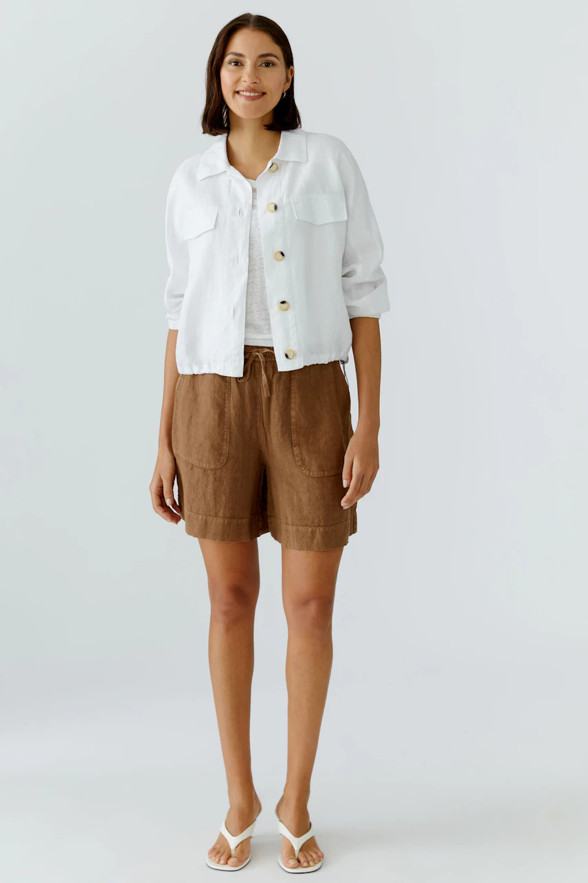 Lässiger Damen-Blouson: Frau im weißen Blouson, kombiniert mit braunen Shorts und weißen Sandalen.