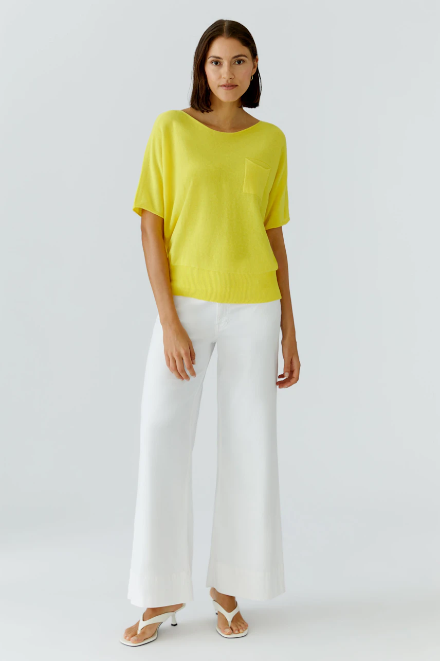 Casual women's pullover: Woman in a yellow pullover with short sleeves and a relaxed fit.