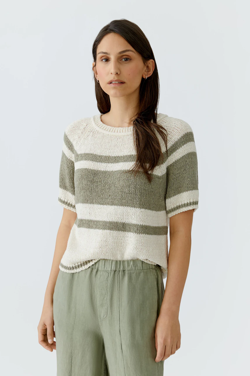 Casual pullover: Woman in a striped short-sleeve pullover with relaxed fit, paired with green pants.