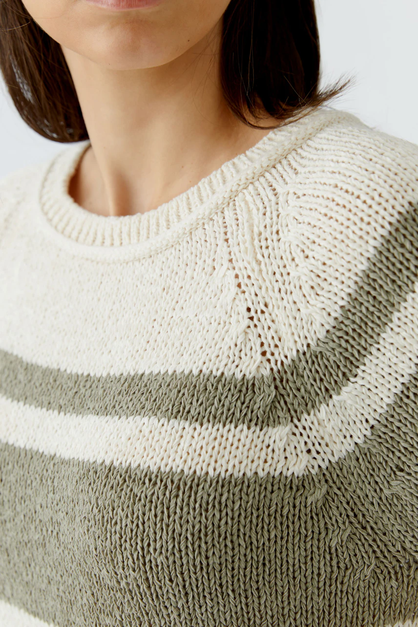 Casual women's pullover: Woman in a cream and olive knit pullover with a relaxed fit.