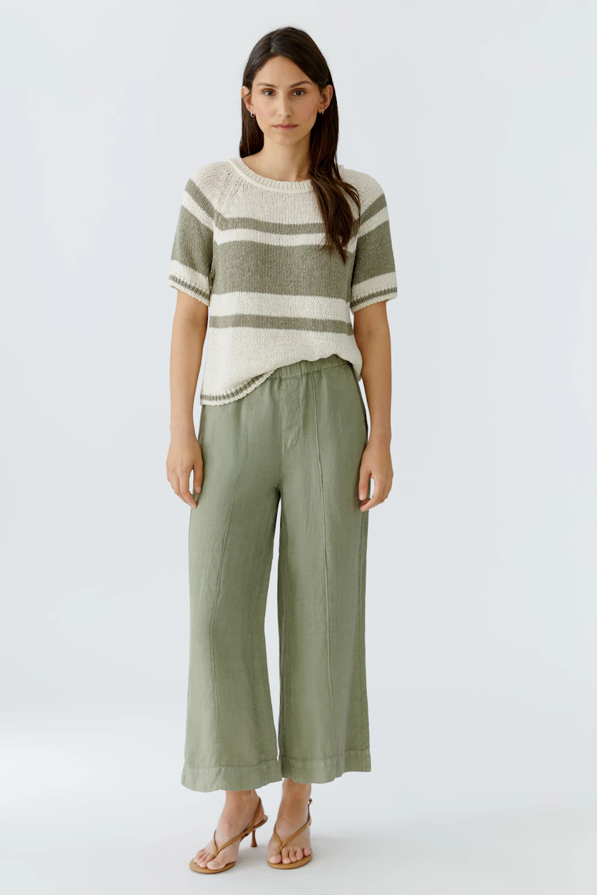 Casual women's pullover: Woman in striped pullover and green wide-leg pants stands confidently.