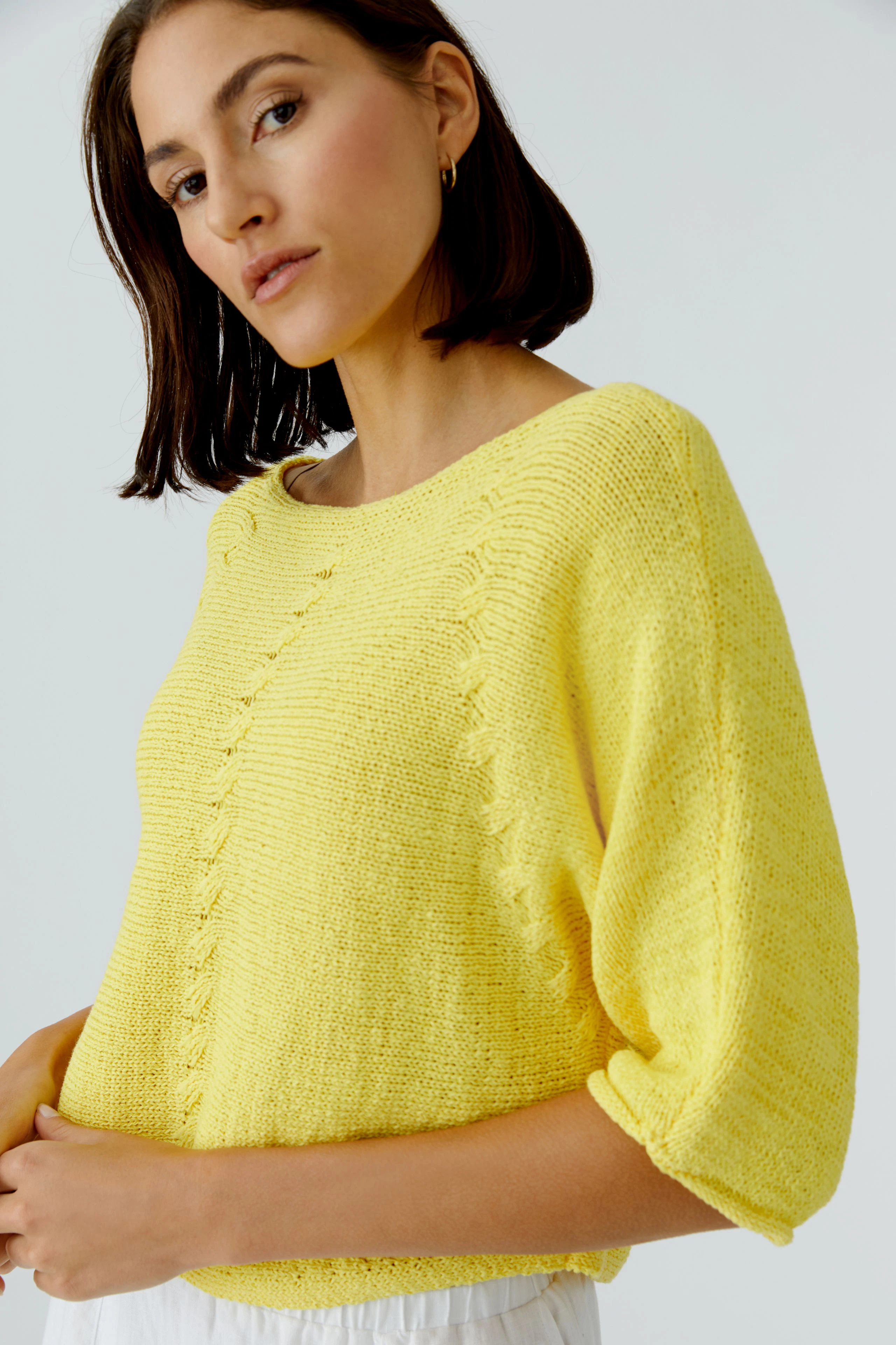 Casual women's pullover: Woman in a bright yellow knit pullover with relaxed fit and round neckline.