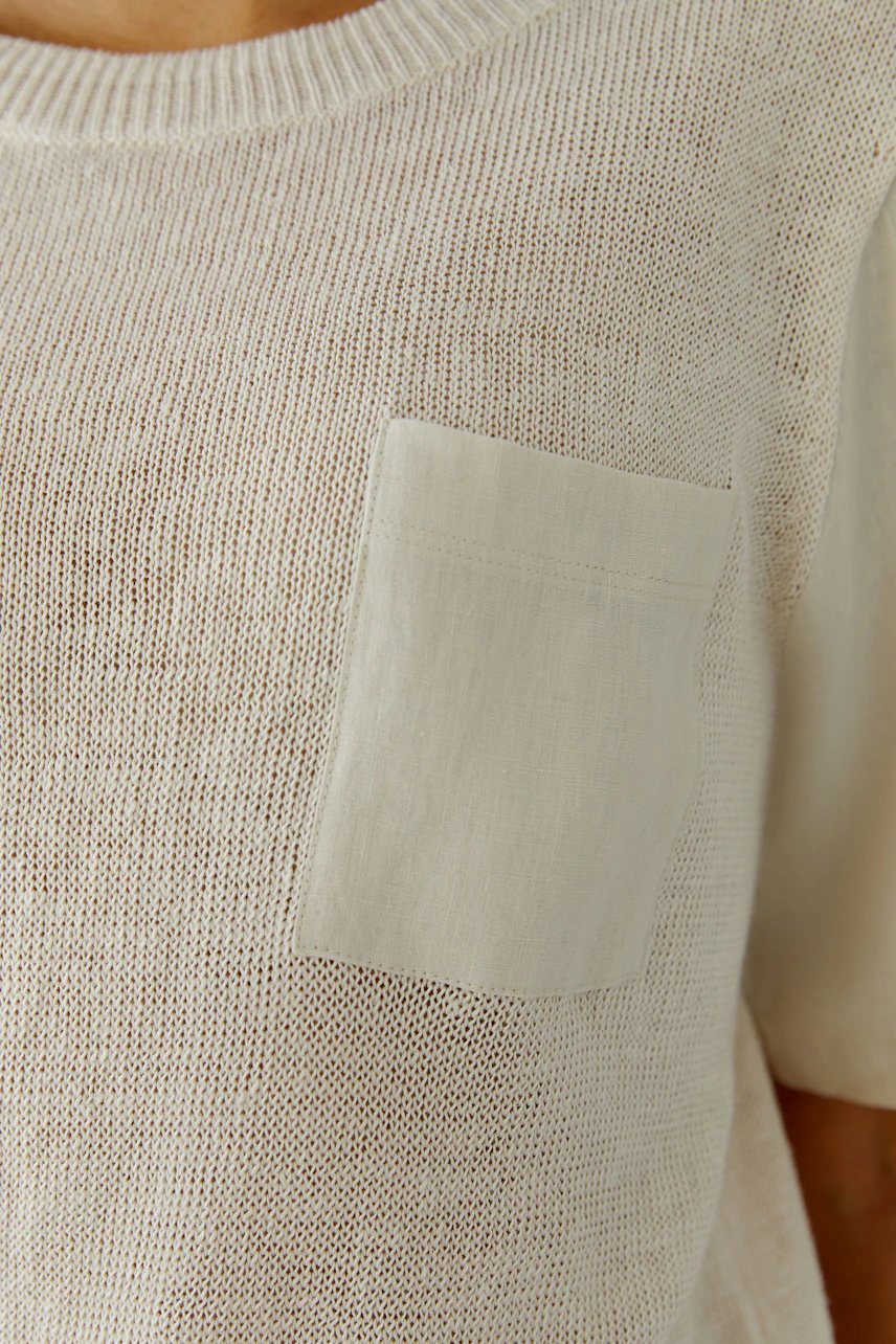 Lässiger Damen-Pullover: Frau trägt beigen Strickpullover mit Brusttasche, ideal für entspannte Looks.