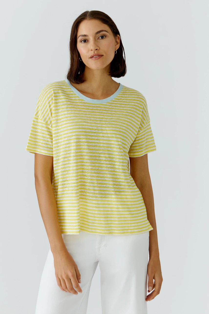 Gestreiftes Damen-T-Shirt: Frau im gelb-weiß gestreiften T-Shirt und weißen Hosen, lässig und modern.