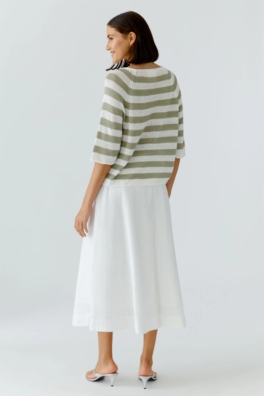 Gestreifter Damen-Pullover: Frau im lässigen Pullover mit weißen und grünen Streifen, kombiniert mit weißem Rock.