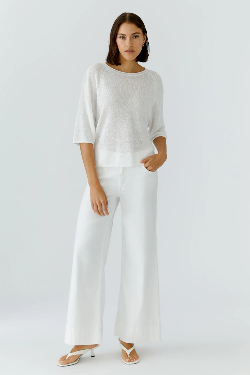 Lässiger Damen-Pullover: Frau im weißen Pullover und weiter Hose, entspannt und modern.