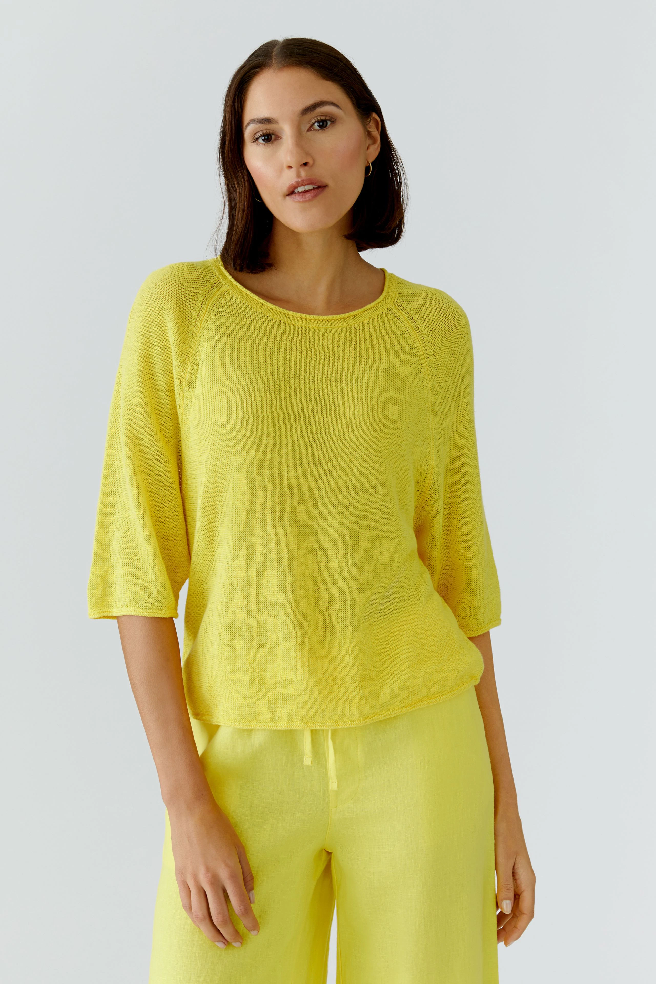 Casual women's pullover: Woman in a bright yellow pullover with matching pants, exuding a relaxed vibe.